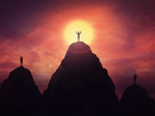 People standing on top of three adjacent mountains.