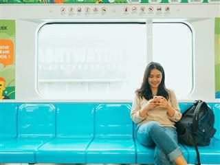 woman looking down at her phone while riding an empty subway