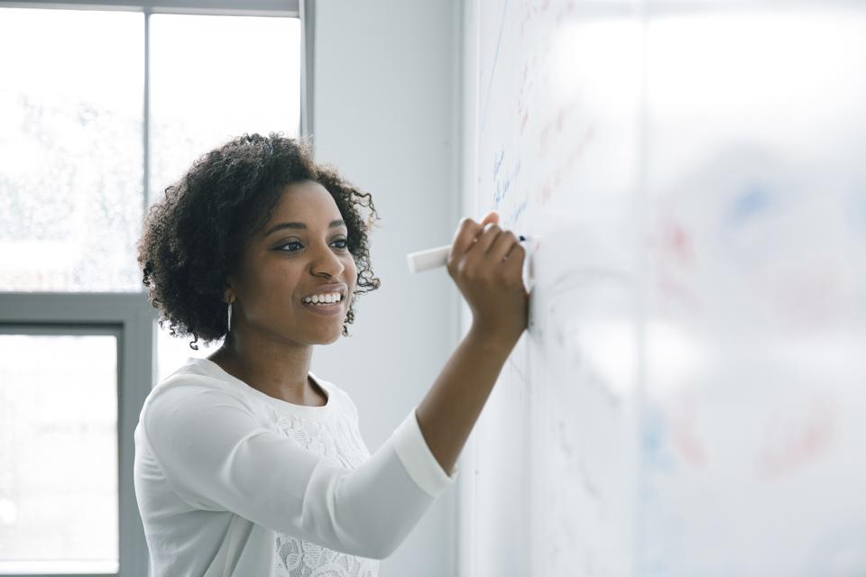 African American businesswoman writing on whiteboard in meeting