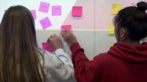 Student-athletes place sticky notes on a whiteboard as part of a class exercise.