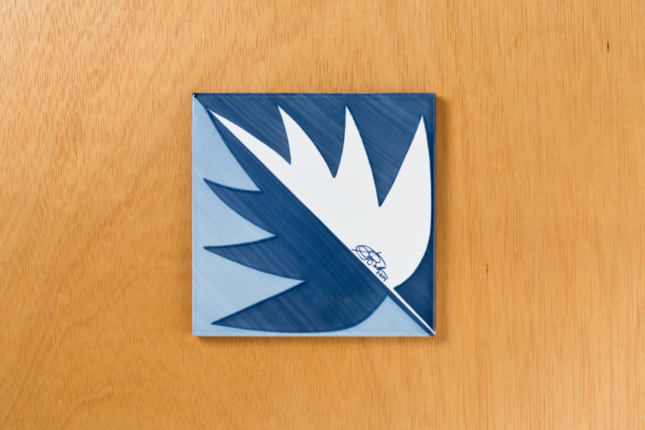 A blue and white tile with a leaf on it