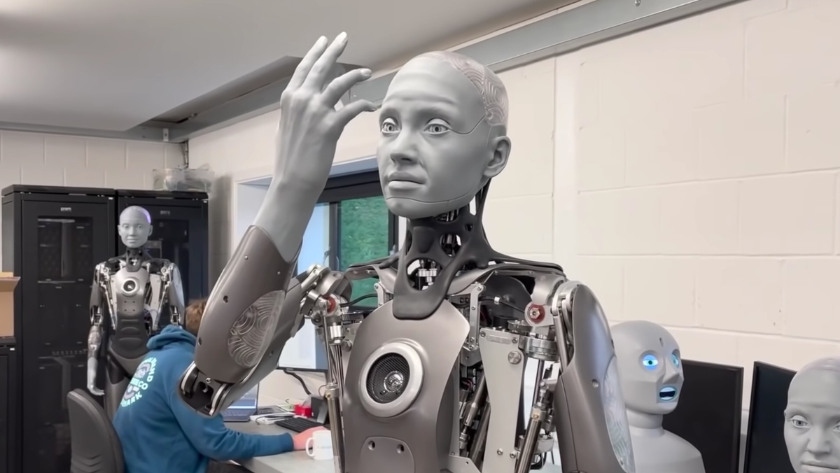 The bipedal humanoid robot, Ameca, looks at its hand in a stunningly humanlike way.