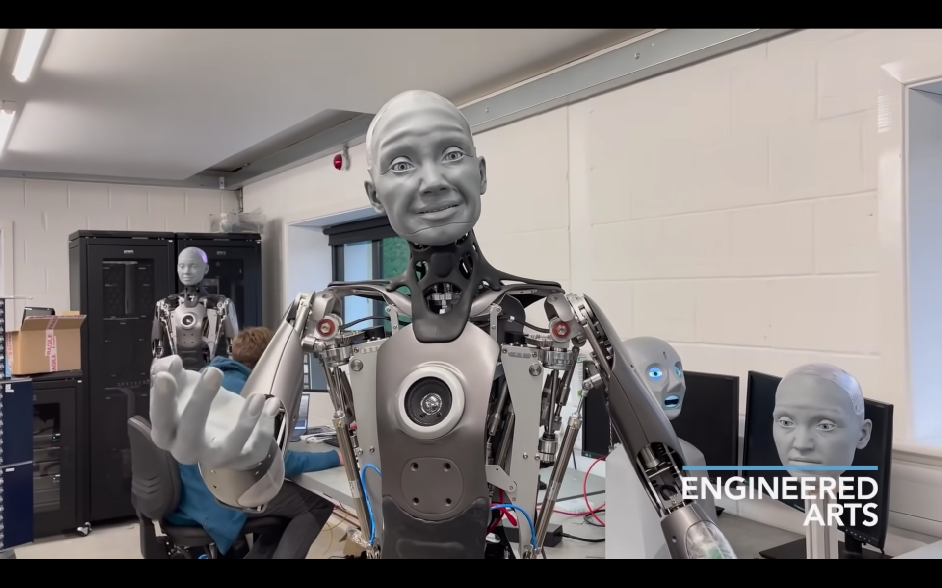 The bipedal humanoid robot, Ameca, looks at its hand in a stunningly humanlike way.