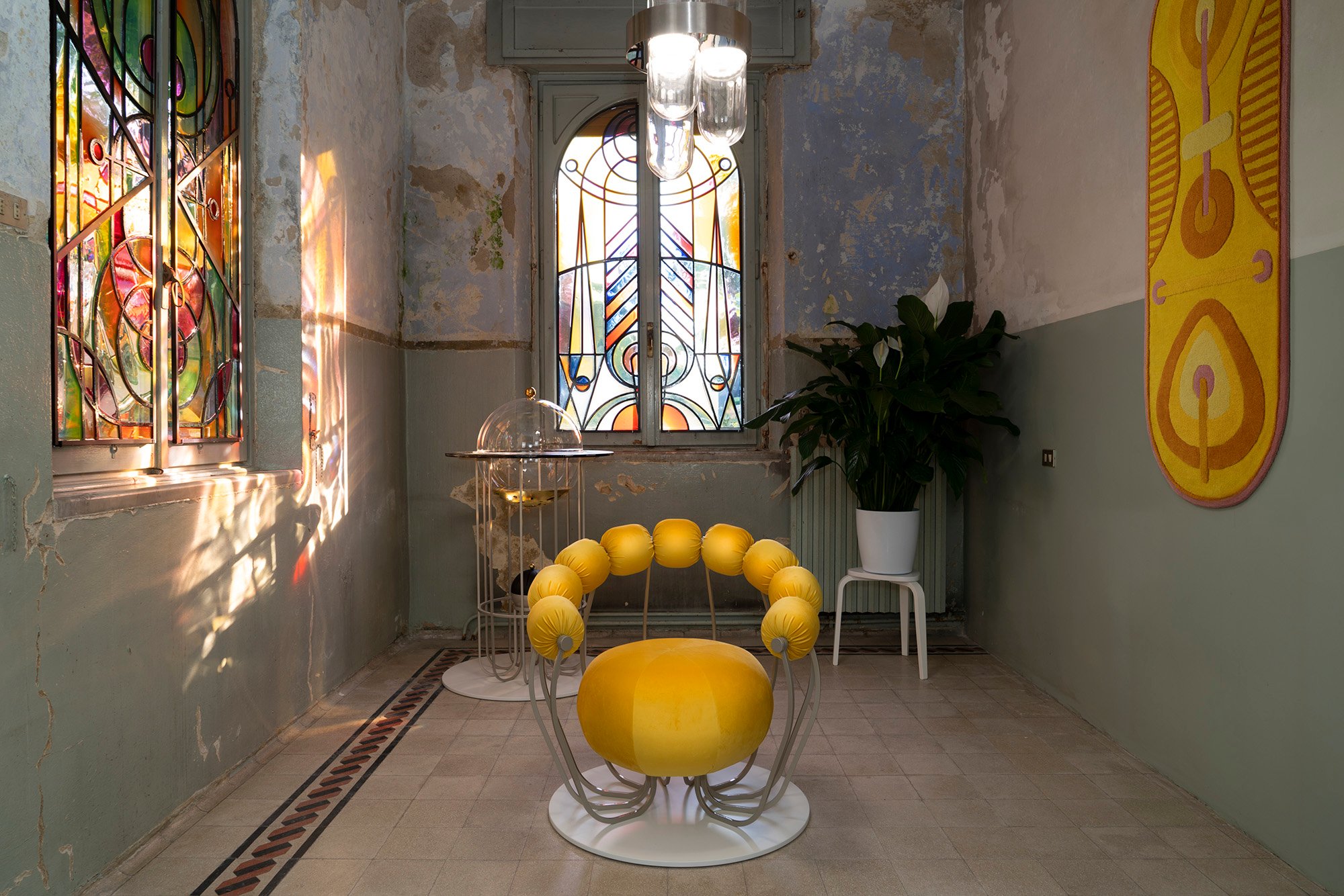 An image of a yellow chair in the middle of a room with stained glass windows
